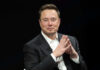 Man in suit clasping hands against black background