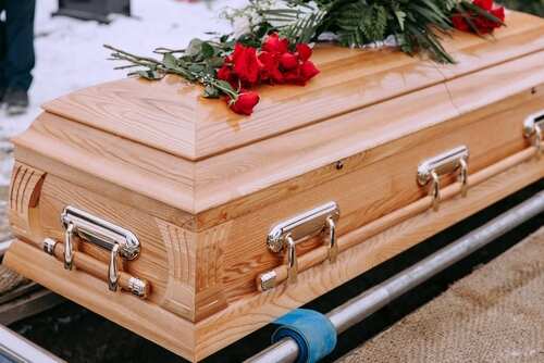 A wooden coffin adorned with red roses at a burial site