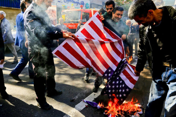 1609051222 Group burning American flag on street pavement