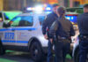 Police officers standing near NYPD vehicles at night