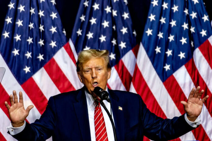 2551951931 Man speaking on stage with American flags behind