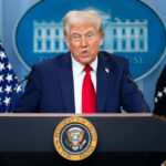 Trump’s Executive Order Triggers Historic Overhaul of U.S. Education System Person speaking at a podium with flags behind
