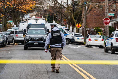 shutterstock_1867892029.jpg Law enforcement officer walking towards a crime scene marked by police tape