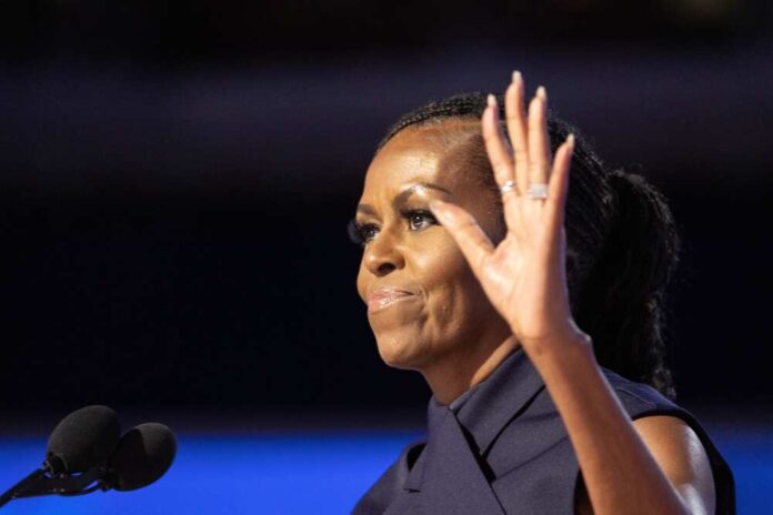 A woman speaking at a podium with a microphone, raising her hand in a gesture