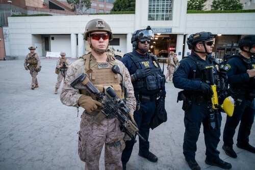 shutterstock_2654860723.jpg Military and police personnel in tactical gear standing in an urban area