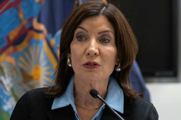 Woman speaking at a podium with flags behind