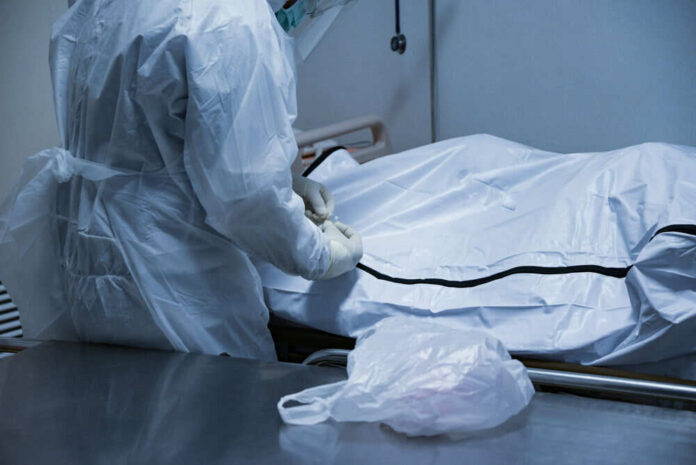 1713746299 Person in protective gear handling body bag