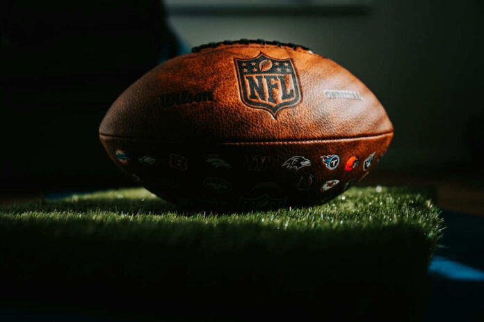 2360209053 NFL football resting on artificial grass indoors