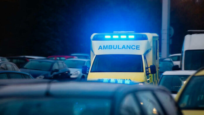 Ambulance with blue lights in traffic at dusk