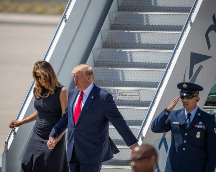 Couple walking down airplane stairs with military personnel