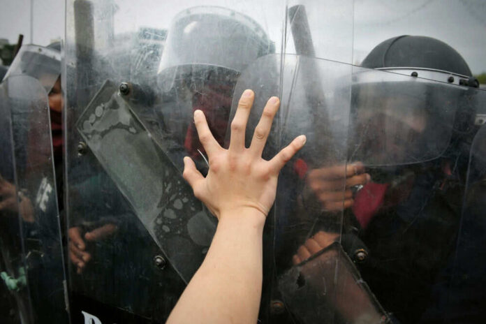Hand reaching out to police riot shields