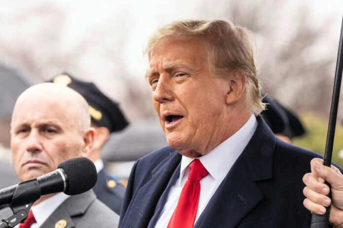 Two men speaking at an outdoor event in suits