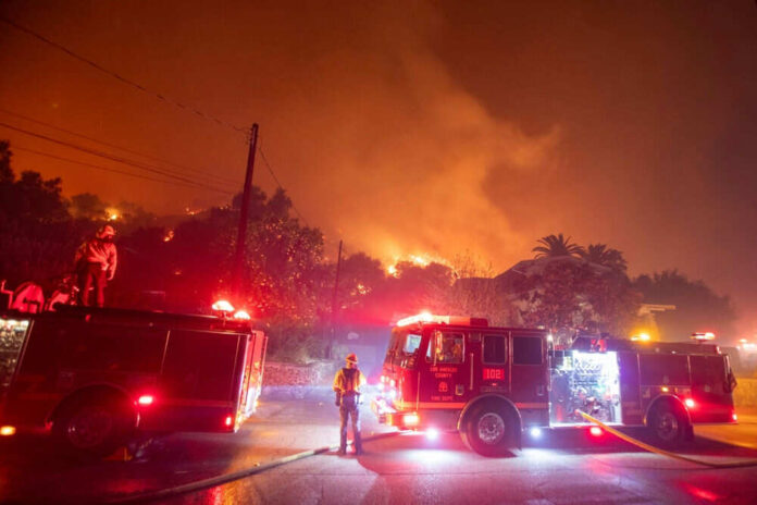 Firefighters battling wildfire with trucks at night