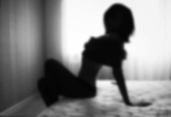 Silhouette of person sitting on bed near window