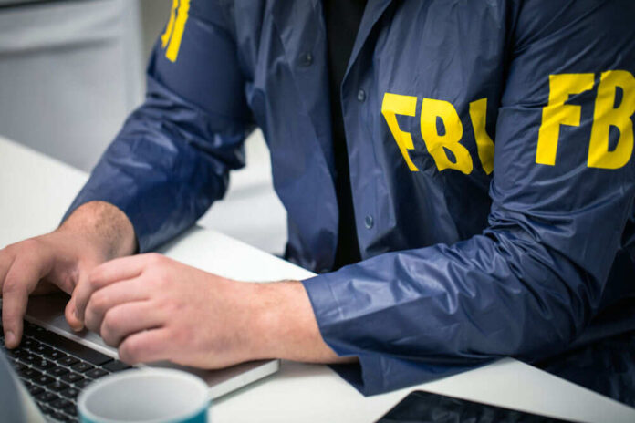 Person in FBI jacket using a laptop