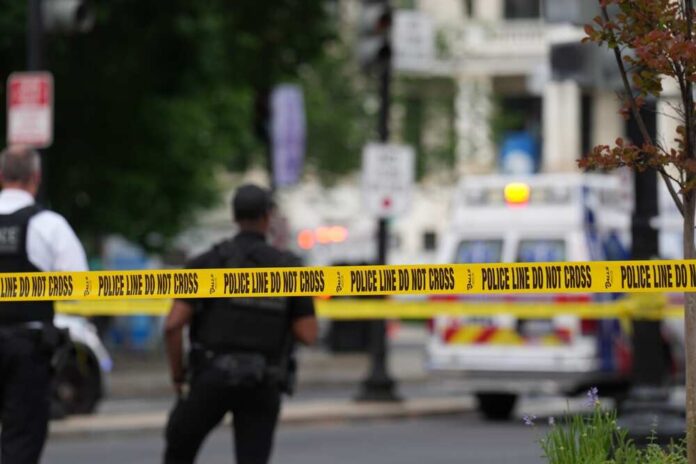 Police officers near a crime scene marked by caution tape