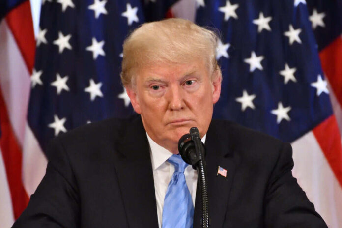 Man speaking at podium with American flags behind him