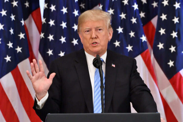 Man speaking at podium with American flags behind