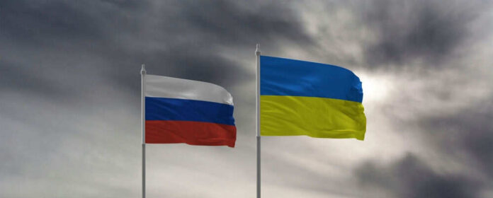 Russian and Ukrainian flags against cloudy sky