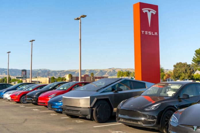 Tesla cars parked near red Tesla sign