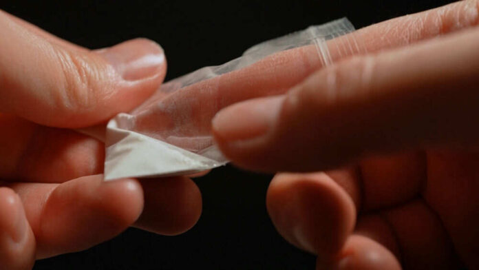 2578912713 Hands holding small plastic bag with white powder