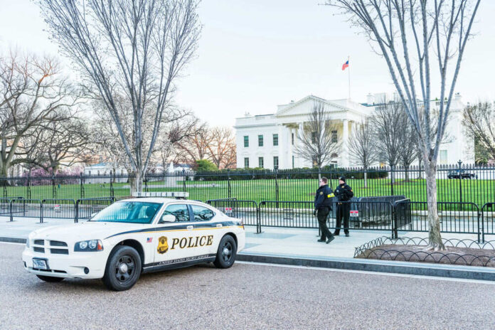 Police car and officers in front of large building