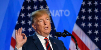 Man speaking at podium with American flags background