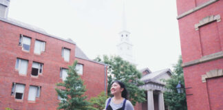 Person walking on a college campus smiling widely