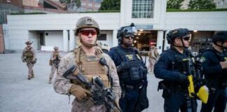 Military and police personnel in tactical gear standing in an urban area