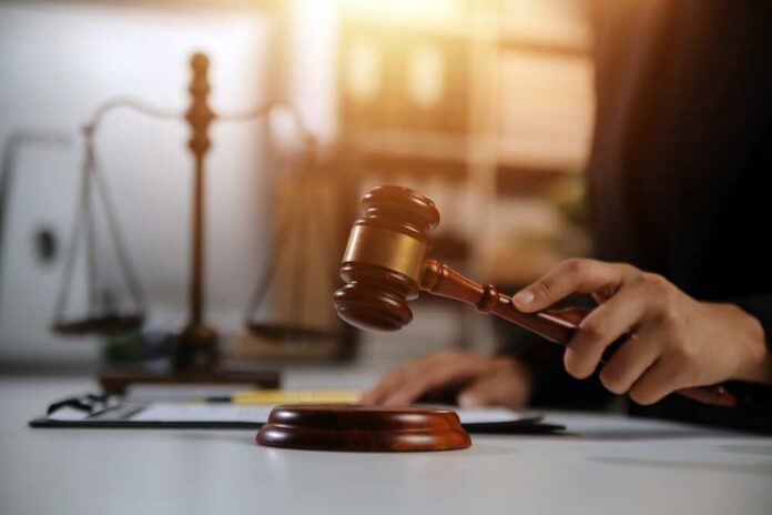 A lawyer striking a gavel on a desk in a courtroom setting